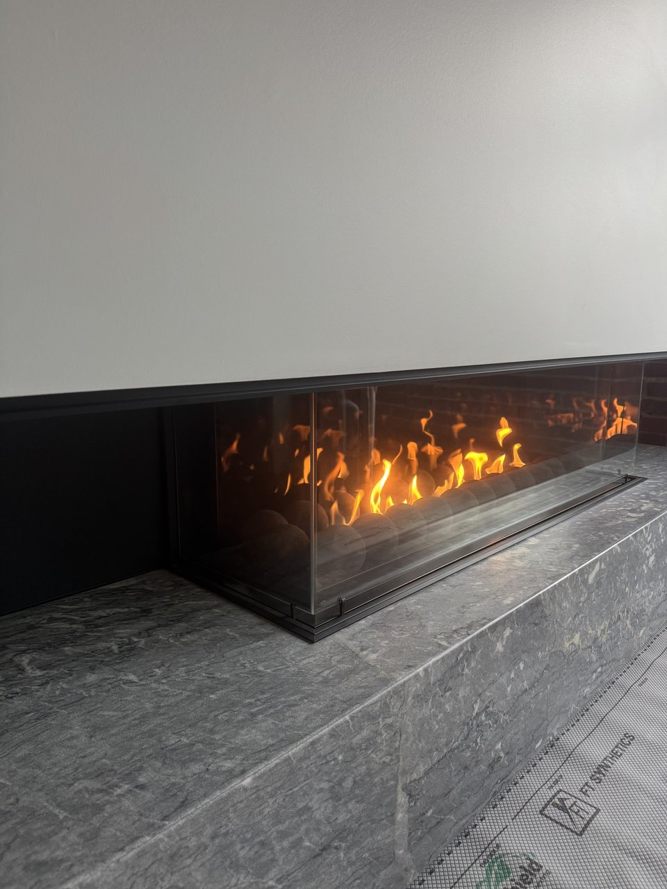 Linear gas fireplace with stone surround in the Powell loft renovation, Vancouver