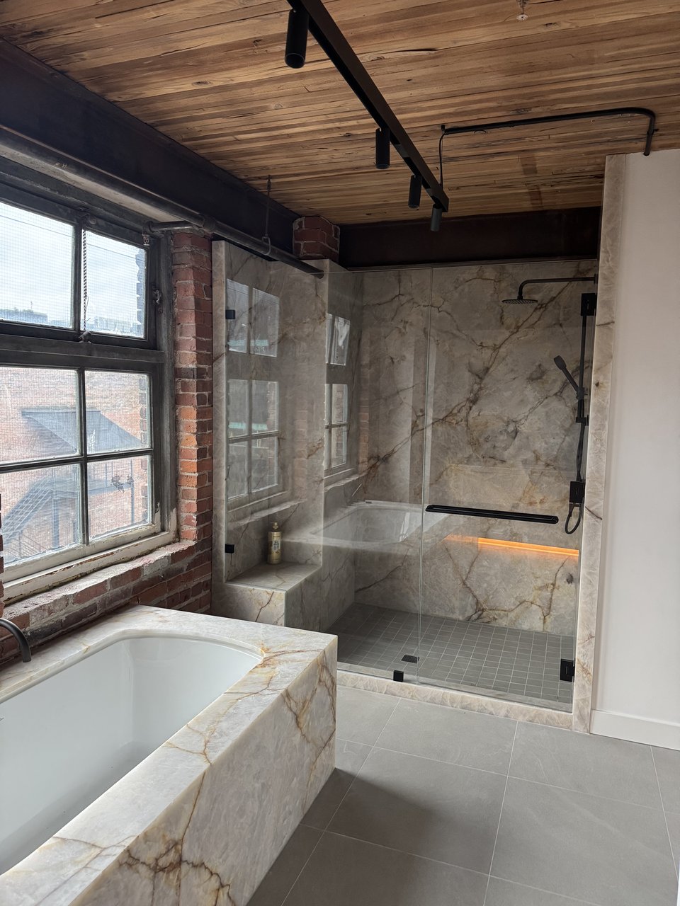 Marble bathroom with soaker tub beside a steel framed window, Powell renovation